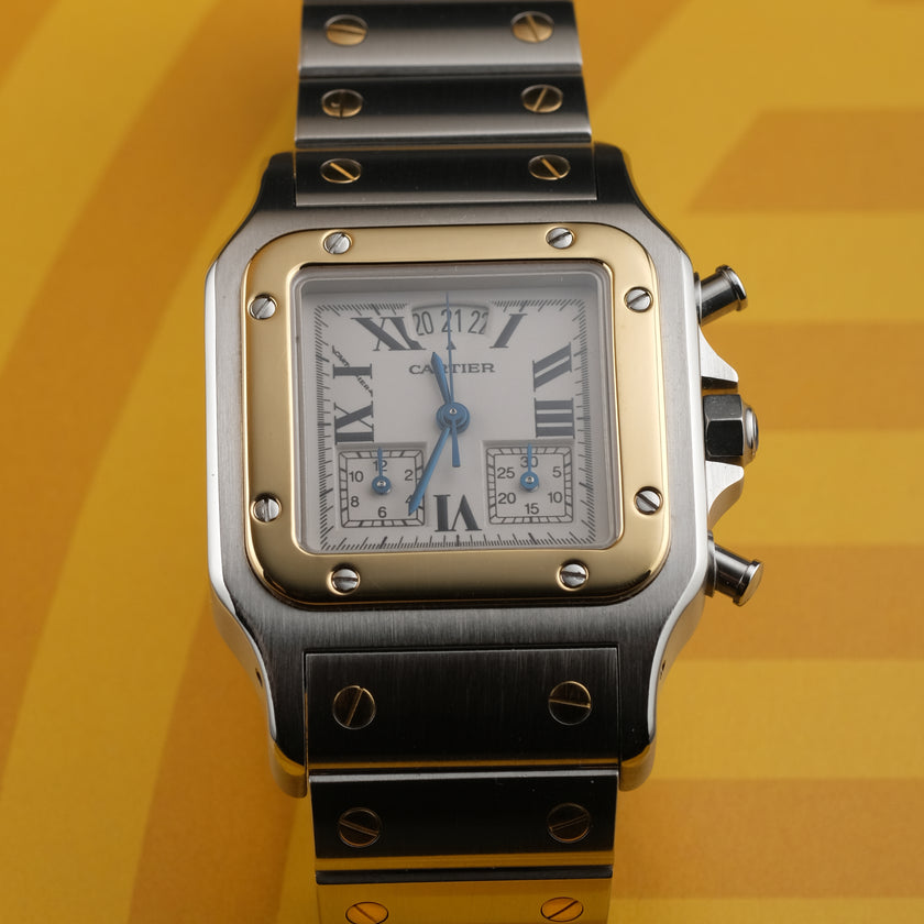 A Cartier watch with a silver-toned stainless steel case and bracelet, a gold-toned bezel, and a white dial with Roman numerals, set against a yellow background.