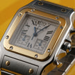 A Cartier watch with a silver-toned stainless steel case and bracelet, a gold-toned bezel, and a white dial with Roman numerals, set against a yellow background.