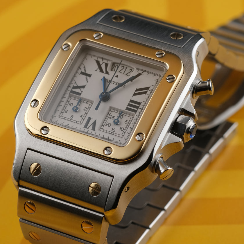A Cartier watch with a silver-toned stainless steel case and bracelet, a gold-toned bezel, and a white dial with Roman numerals, set against a yellow background.