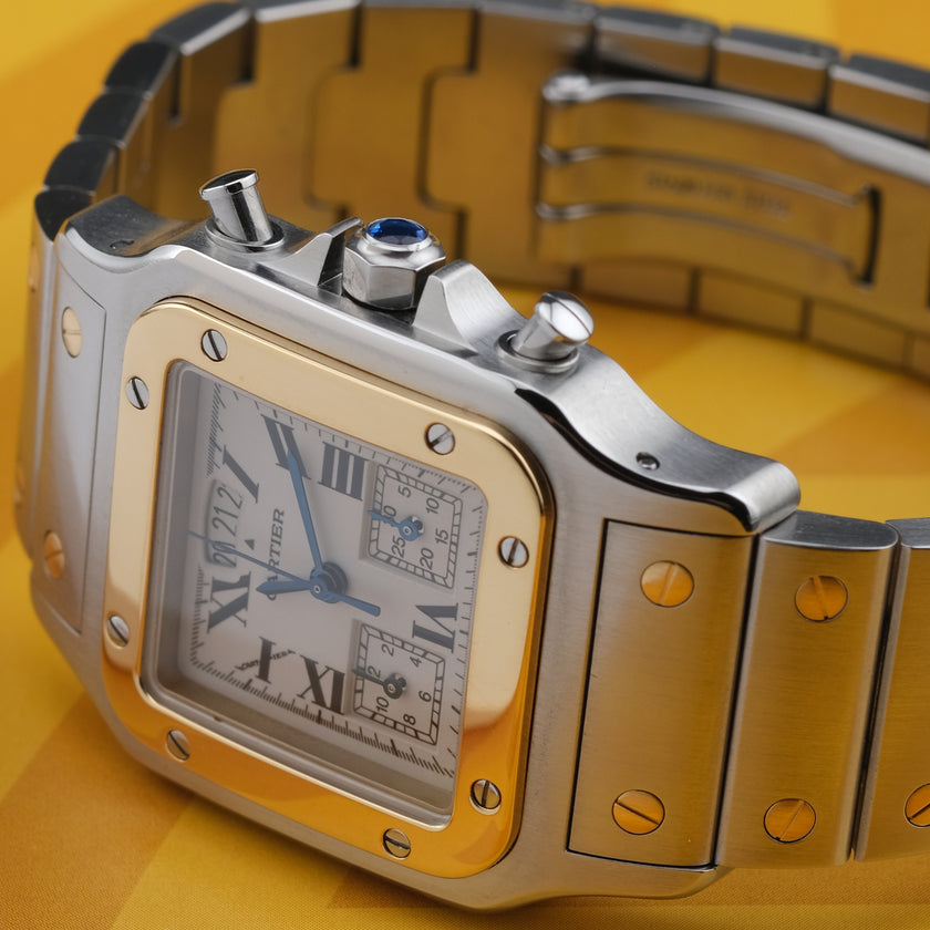 A Cartier watch with a silver-toned stainless steel case and bracelet, a gold-toned bezel, and a white dial with Roman numerals, set against a yellow background.