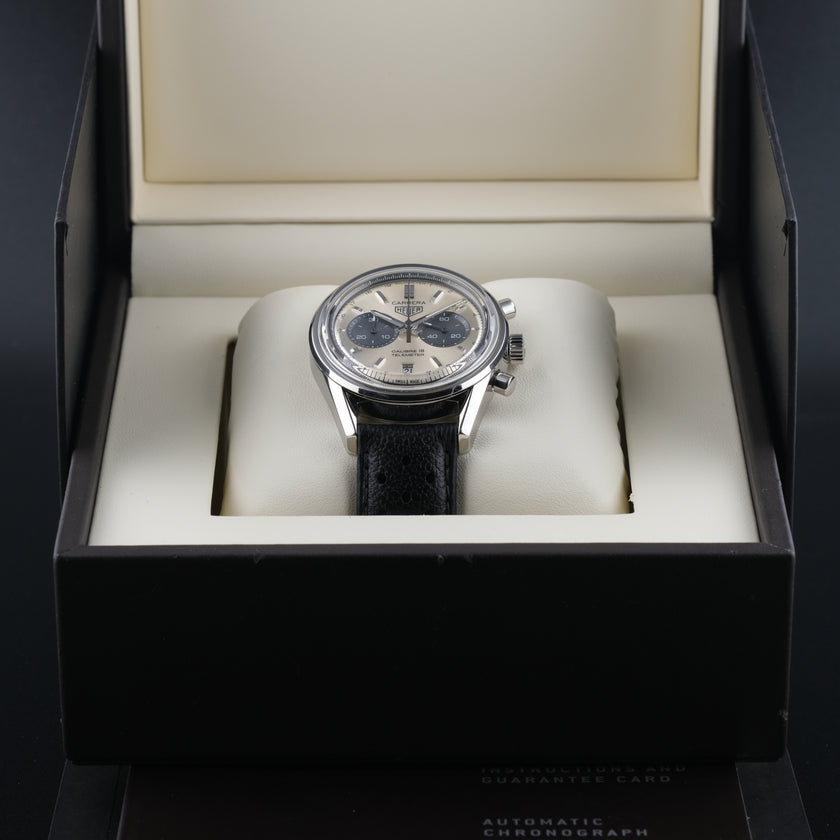 A TAG Heuer Carrera 18 Telemeter wristwatch with a silver-toned stainless steel case, a champagne dial, black subdials, and a black leather strap, shown in a close-up shot.