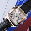 A Cartier watch with a square silver-toned case, gold-tone bezel, white dial with black Roman numerals, and a black crocodile-embossed leather strap, shown close-up against a graphic blue, red, and white background.