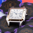 A Cartier Santos watch with a silver-toned stainless steel case, gold-tone accents, and a white dial with Roman numerals, resting on a stack of black and purple poker chips.