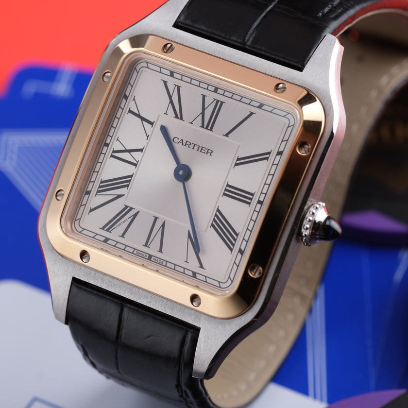 Cartier Santos watch with a silver-toned stainless steel case, gold-toned bezel, white dial with black Roman numerals, and a black leather strap.